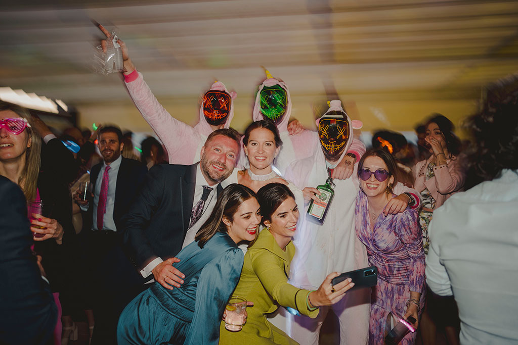 Fotografía de invitados y novios con mascaras en la hora loca