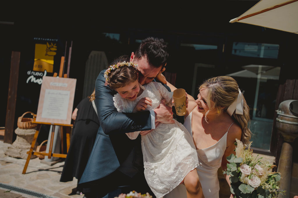 Abrazo de los novios con su hija en su boda